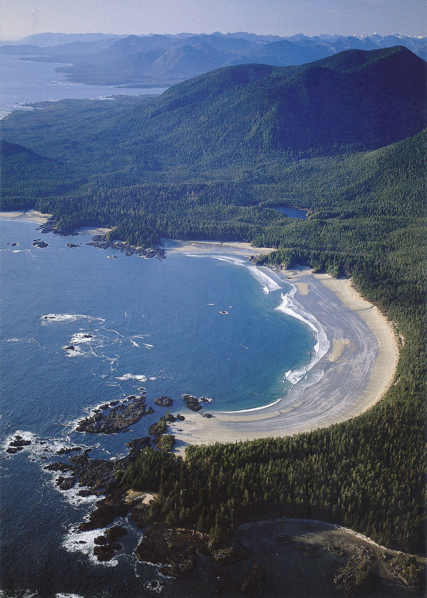 An aerial shot of Flores Island - there is a beach surrounded by mountains and forests. End of image description.