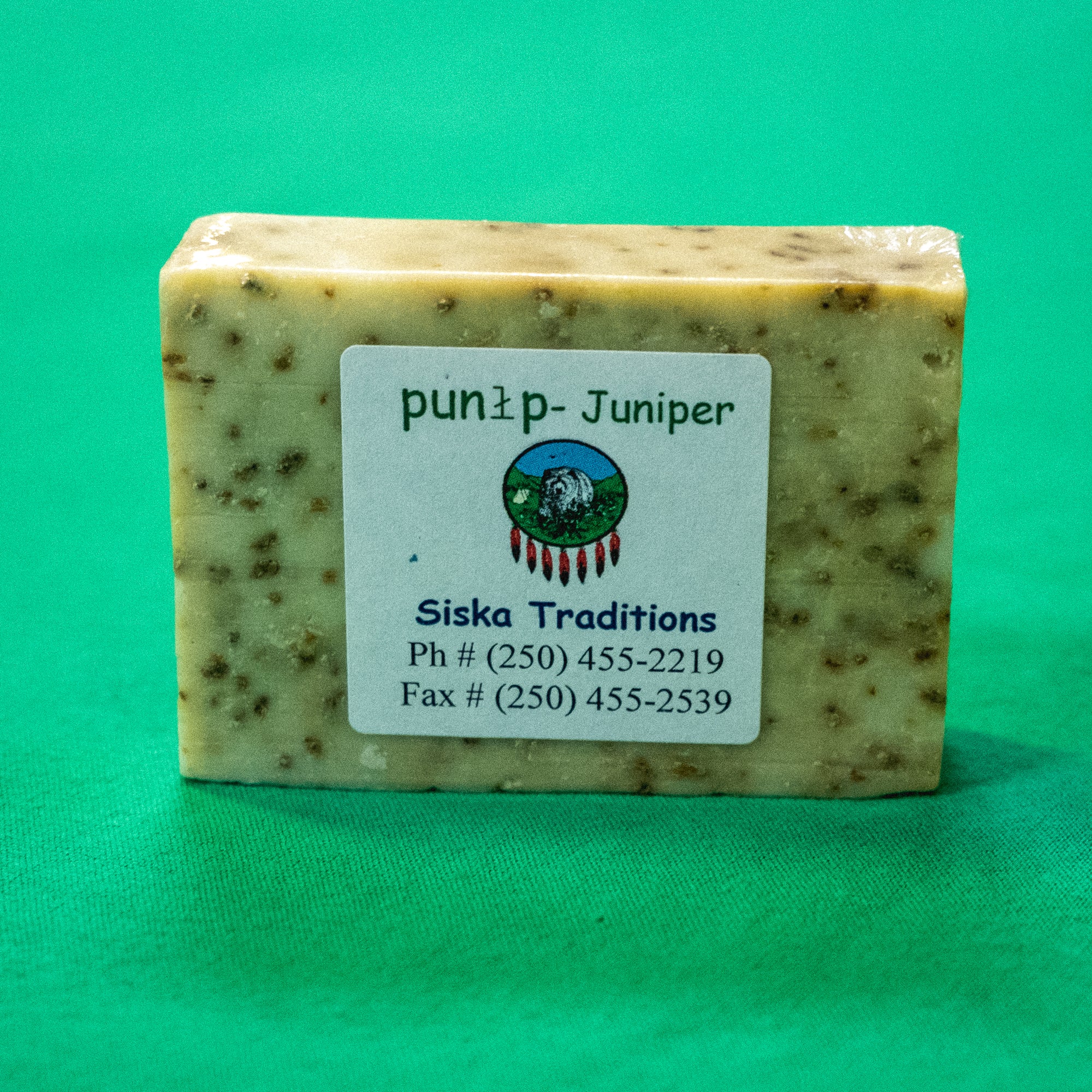 A bar of soap with a label on it that says "Punłp - Juniper. Siska Traditions. Phone: 250-455-2219. Fax: 250-455-2539." End of image description.