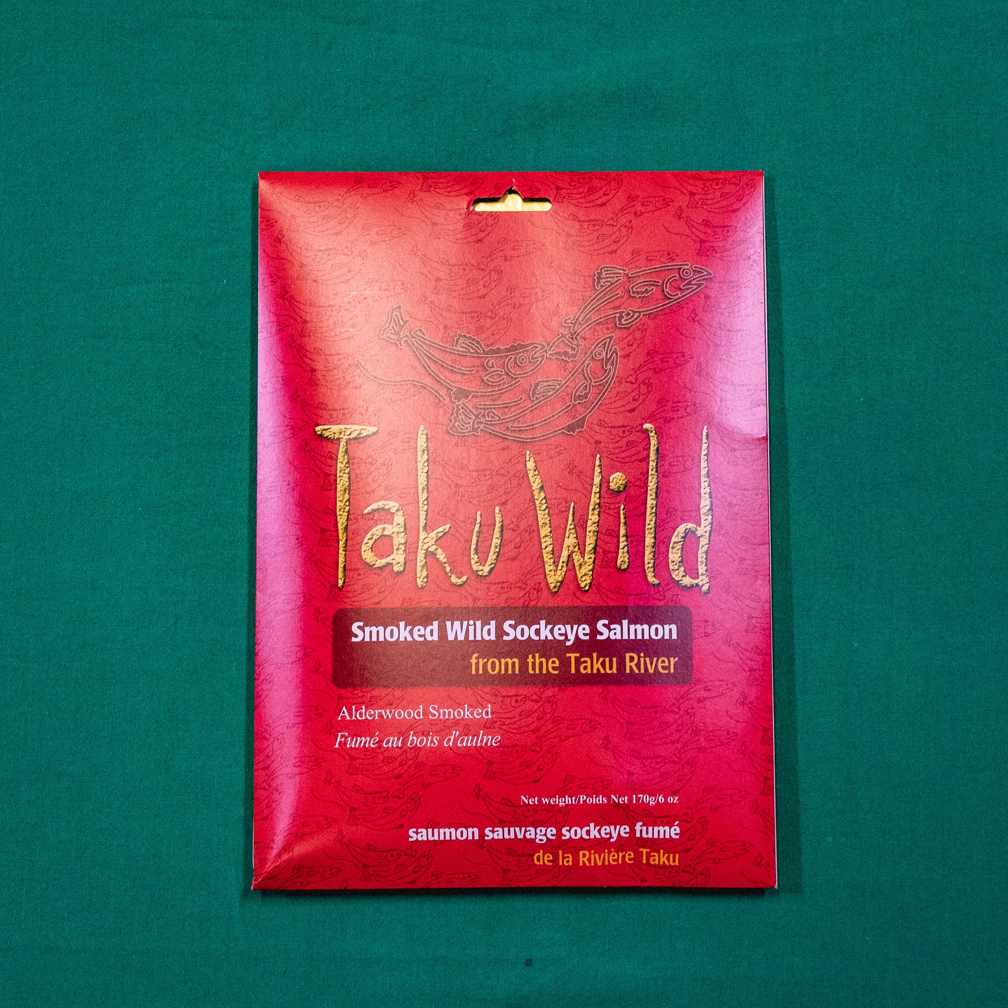 A packet with illustrations of salmon. Text on the image says "Taku Wild. Smoked Wild Sockeye Salmon from the Take River. Alderwood Smoked." End of image description.